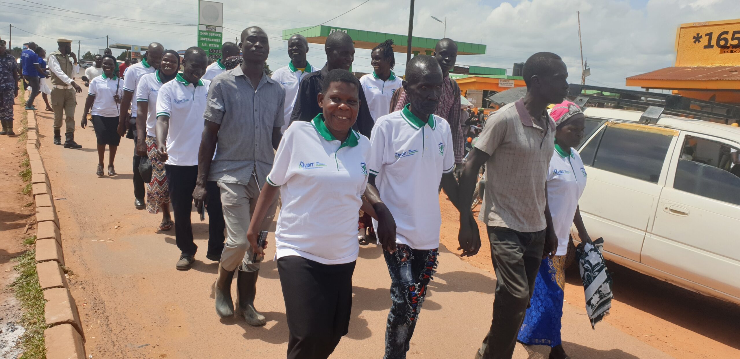 Ms Arube (left) in white holding hands with visually impaired beneficiary during community awareness in Koboko.